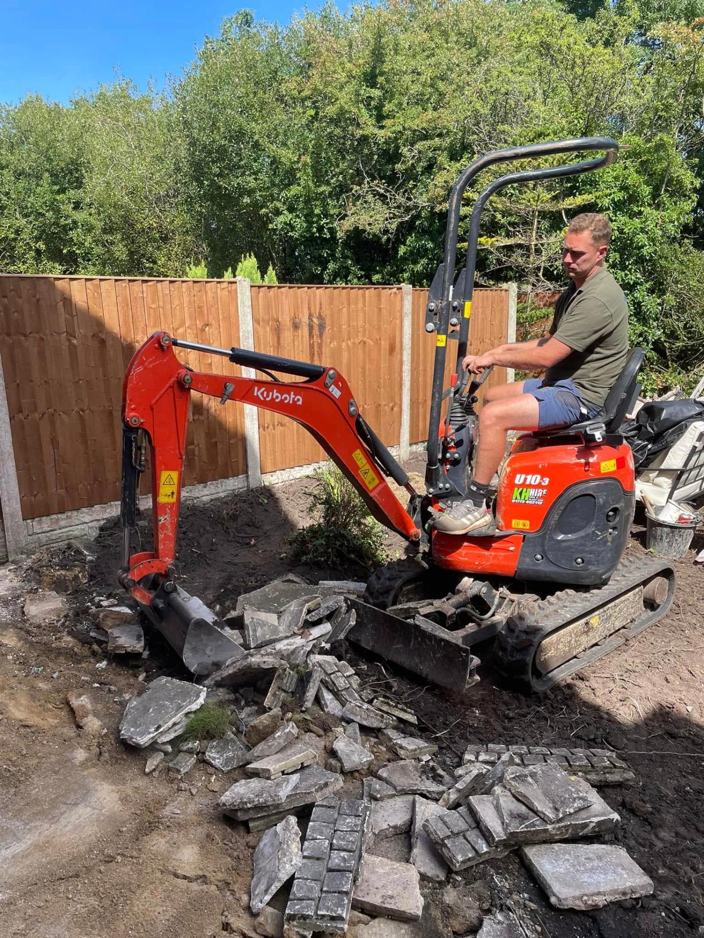 Crew member lifting an old concrete patio with a Kubota mini-excavator