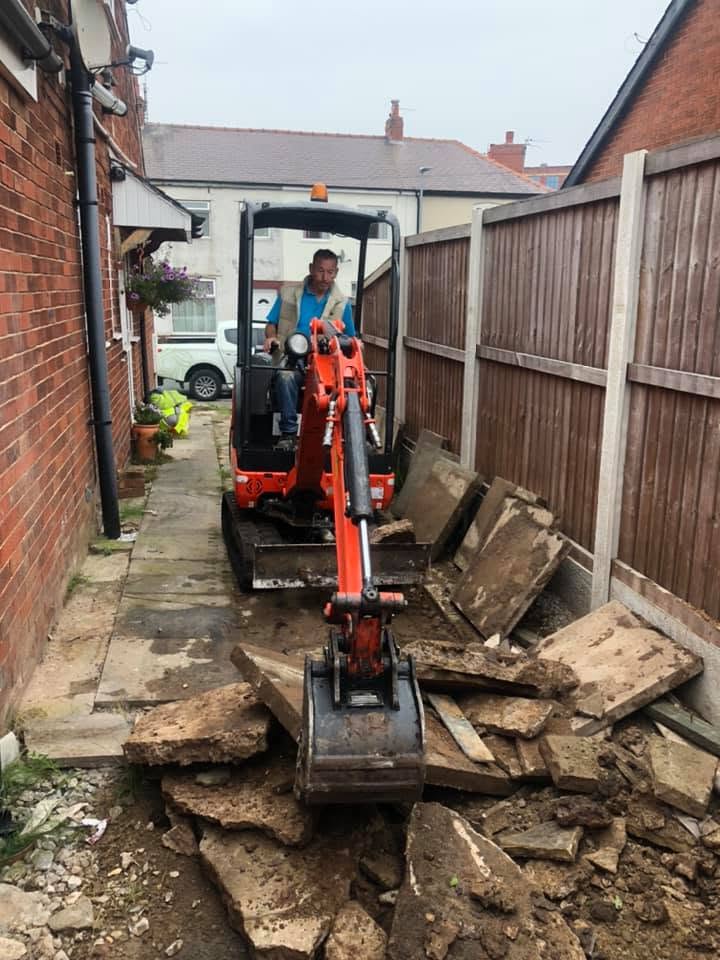 Noel operating a Kubota mini-digger to lift old flagstones from a narrow side alley