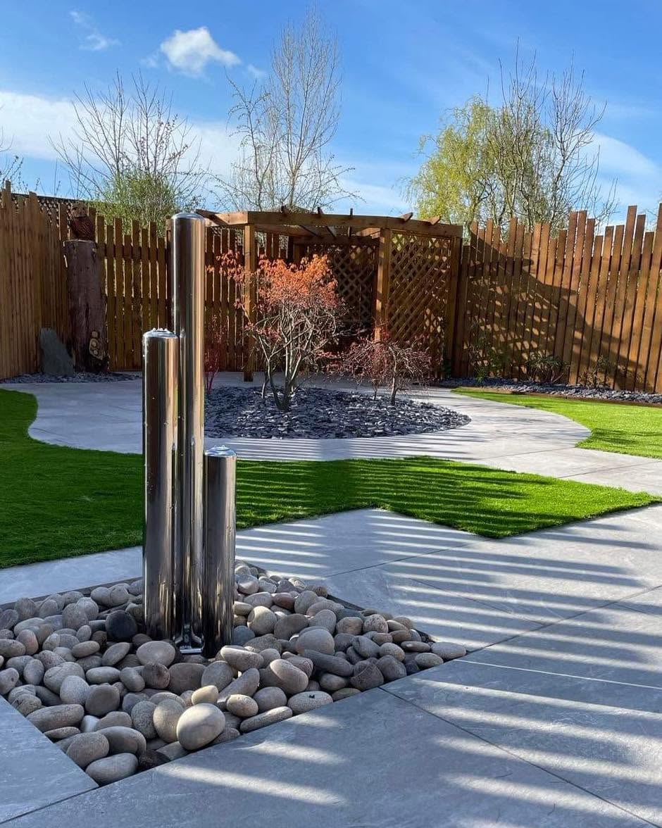 A stunning contemporary garden with stainless steel water feature, curved artificial grass and autumn Japanese maple, built by Croston Landscape Services